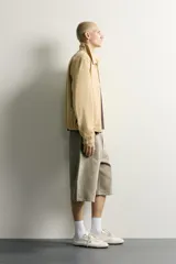 Cazadora regular fit de color beige, confeccionada en mezcla de algodón y lyocell. Cuenta con cuello camisero, cierre frontal de cremallera, bolsillos de plastrón en la cadera, mangas largas con puños elásticos y bajo con ajuste elástico.