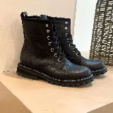 Borcego de cuero vacuno color negro, con diseño acordonado, suela de goma dentada y cierre lateral interno.