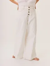 Pantalón ancho de algodón color blanco crudo, con tiro alto y cierre frontal de botones oscuros. Presenta costuras contrastantes en tono camel o beige claro.