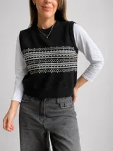 Chaleco tejido de punto con diseño geométrico en contraste blanco y negro, cuello redondo y terminaciones acanaladas.