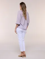 Blusa de gasa de color lila con calce holgado, cuello a la base con escote en V y cartera de botones a tono. Cuenta con fruncidos en el cuello y hombros que otorgan volumen, manga tres cuartos estilo abullonado con puño elastizado y ruedo suavemente redondeado.