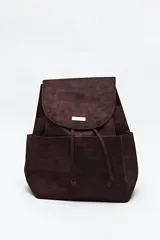 Mochila de símil gamuza color negro con textura tipo reptil. Presenta un diseño minimalista con solapa frontal, cierre de cordón ajustable y bolsillos laterales. Incluye un detalle metálico rectangular en la solapa.