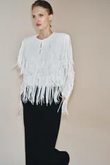Chaqueta de cuello redondo y manga larga con hombreras, completamente cubierta de flecos con lentejuelas. Cuenta con forro interior y cierre frontal.