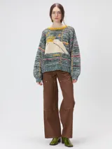 Sweater de punto con diseño geométrico y gráfico frontal en color rojo. Presenta cuello redondo, mangas largas holgadas y un ajuste suelto.