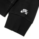 Canguro Nike SB negro con capucha y cordones ajustables. Presenta un diseño gráfico circular con el logo de Nike SB en relieve de textura afelpada blanca en el centro y un pequeño logo bordado en el puño.