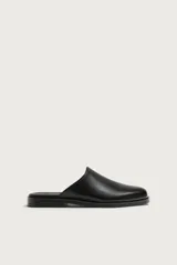 Zueco de vestir para hombre confeccionado en piel de color negro, con horma redonda, diseño destalonado y suela plana a tono.
