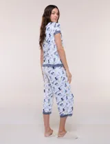 Conjunto pijama de pantalón capri y remera René Rofé, de color blanco con estampado floral en tonos azules y celestes. Remera de manga corta con escote en V y detalles de encaje azul en el escote, las mangas y el ruedo. Pantalón capri con cintura elastizada, cordón de ajuste y encaje en el ruedo.