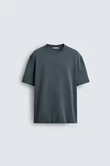 Camiseta de corte relajado confeccionada en tejido interlock de algodón con elasticidad, presenta cuello redondo y manga corta.