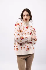 Polera de tejido de punto con cuello alto, diseño holgado y estampado jacquard con motivos geométricos y figuras en tonos beige, naranja y celeste.
