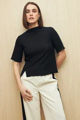 Top negro de textura acanalada con cuello semi alto y mangas largas. Presenta un diseño ajustado al cuerpo con una sutil abertura lateral en el ruedo.