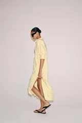 Vestido midi camisero de algodón, color amarillo con estampado a cuadros. Cuenta con cuello solapa, escote en V, mangas cortas con puño y bolsillos laterales ocultos en la costura, con diseño evasé.