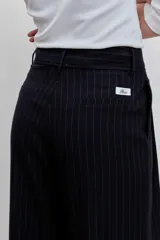 Pantalón de vestir negro con rayas verticales blancas, de corte recto y tiro alto.