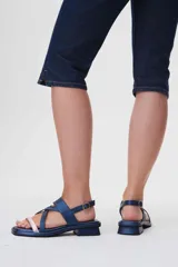 Sandalias de cuero azul con tiras cruzadas y hebilla lateral. Presenta una tira delantera color rosa claro.