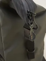 Bolso tipo duffel verde militar con base y detalles en negro. Tiene doble asa de mano y correa de hombro ajustable y extraíble. Cuenta con dos bolsillos frontales con cierre y logo de la marca en la parte inferior.