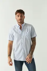Camisa de manga corta con estampado de microcuadros en tonos celestes y blancos. Presenta cuello abotonado, cierre frontal con botones y un bolsillo en el pecho con el logo de la marca bordado.