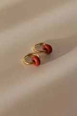 Par de aros tipo argolla dorados de acero quirúrgico, con una piedra natural de color gris translúcido colgando de cada uno.