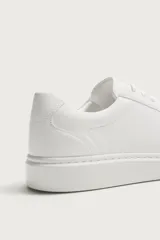 Zapatilla urbana monocolor blanca con cordones al tono, diseño de parte superior lisa, puntera redondeada y suela con volumen.