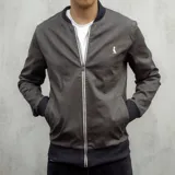 Campera bomber gris plomo de gabardina, con cuello, puños y cintura de punto elástico en color gris oscuro. Cierre frontal con cremallera y logo bordado en el pecho.