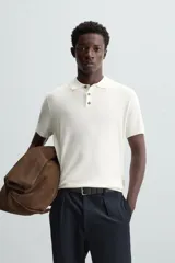 Polo de punto negro, manga corta, con cuello solapa y cierre frontal de tres botones. Presenta un calce regular y acabados en rib en mangas y ruedo.