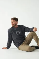 Buzo de felpa color beige con cuello redondo, manga larga y puños acanalados. Presenta un logo circular estampado en el frente.