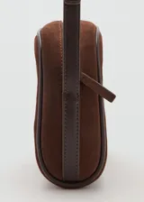 Bolso bandolera de tamaño pequeño confeccionado en piel de serraje color marrón. Cuenta con cierre de cremallera, forro interior de algodón y asa larga ajustable con hebilla metálica.