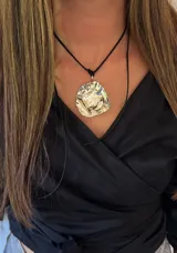 Collar con cordón de cuero negro y dije grande irregular de alpaca plateada.