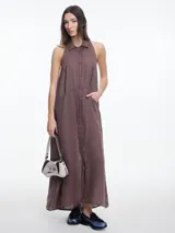 Vestido largo sin mangas color marrón, confeccionado en lino, con cuello camisero y espalda descubierta con ajuste regulable. Presenta bordado tipo pespunte en contraste sobre el cuello.