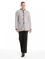 Cardigan de tejido de punto con diseño de espiga en color beige, totalmente forrado en corderito sintético blanco. Presenta cuello solapa, cierre frontal con botones, bolsillos tipo parche con solapa y terminaciones con vivos en contraste.