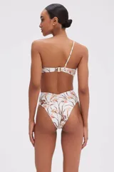 Vestido largo de corte midi con estampado floral en tonos suaves sobre base off-white. Presenta escote corazón con detalle de volantes en los hombros, cuerpo estilo corset y falda con volantes asimétricos y abertura frontal.