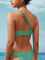 Bikini de una pieza con diseño de un solo hombro, confeccionada en tela texturizada color salmón. Presenta un detalle de argolla decorativa en el hombro y copas removibles.