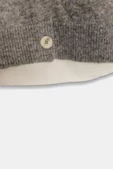 Chaqueta de punto de cuello redondo y manga larga, con diseño combinado que incluye una capa interior en tono crudo. Presenta cierre frontal con botones y puños acanalados.