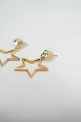 Par de caravanas colgantes con diseño de estrella calada en color dorado, con un pequeño cristal incrustado en la parte superior.