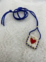 Collar con dije rectangular bordado con un corazón rojo y detalles de mostacillas de colores.