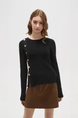 Remera de algodón de calce ajustado, con cuello redondo y manga larga. Presenta una hilera de botones decorativos dorados en el hombro y lateral derecho.