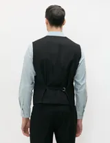Chaleco de vestir negro de corte clásico, con escote en V, cierre frontal de cinco botones y bolsillos ojal simulados en los laterales y el pecho.