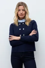 Chaqueta tejida de punto en color azul marino, con diseño de doble botonadura frontal y bolsillos aplicados. Presenta un cuello desmontable en tono claro y mangas largas.