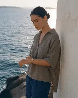 Blusa de lino color blanco, con cuello camisero y escote en V profundo, mangas 3/4 y corte holgado.