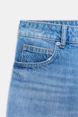 Shorts de denim de tiro medio, color celeste claro con efecto lavado y desgaste sutil. Diseño de cinco bolsillos con cierre frontal de cremallera y botón metálico.