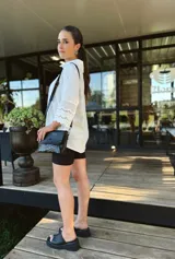 Cartera bandolera de cuero negro con textura tipo cocodrilo, correa larga regulable y forro interno de tela.