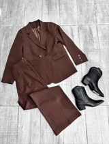Conjunto sastrero de dos piezas color marrón, compuesto por un blazer oversize de botonadura doble y un pantalón de tiro alto de corte recto.