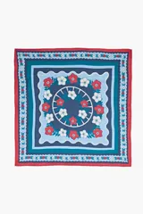 Pañuelo cuadrado con diseño de estampado floral y geométrico en tonos azules, rojos y blancos, con borde en color rojo.