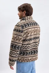 Buzo de sherpa con medio cierre frontal, cuello alto y estampado geométrico abstracto en tonos beige, marrón y negro.