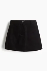 Pollera corta negra de corte evasé, confeccionada en pana con textura acanalada. Presenta cierre y botón frontal.