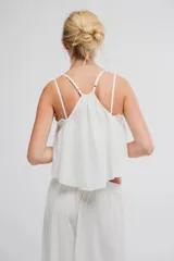 Musculosa blanca de tela liviana con caída amplia, escote en V con aplique de encaje, tirantes finos regulables y diseño corto.