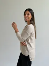 Sweater de punto fino en color beige, con escote en V y mangas largas con puños ajustados.