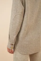 Camisa estilo leñador color beige con textura en espiga, de manga larga, con cuello clásico, cierre frontal con botones, dos bolsillos de parche con solapa abotonada en el pecho y puños abotonados. Confeccionada en lana fina sin teñir.