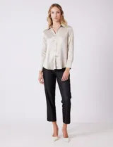 Camisa de satén color verde oliva, con cuello clásico, cierre frontal con botones metálicos y mangas largas con puños abotonados.