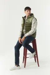 Chaleco negro acolchado con capucha ajustable, cierre frontal y bolsillos laterales con cierre. Logo de la marca en el pecho. Colección Otoño Invierno 2025. El modelo usa talle M. Composición 100% nylon.