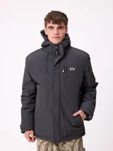 Campera Rusty de estilo técnico, color gris oscuro, con capucha ajustable, cierre frontal con solapa y bolsillos laterales. Presenta logo de la marca estampado en el pecho.