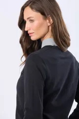 Buzo tejido en hilo de algodón color beige, con cuello redondo y manga larga. Presenta un corte clásico y un pequeño detalle metálico en la parte inferior izquierda.